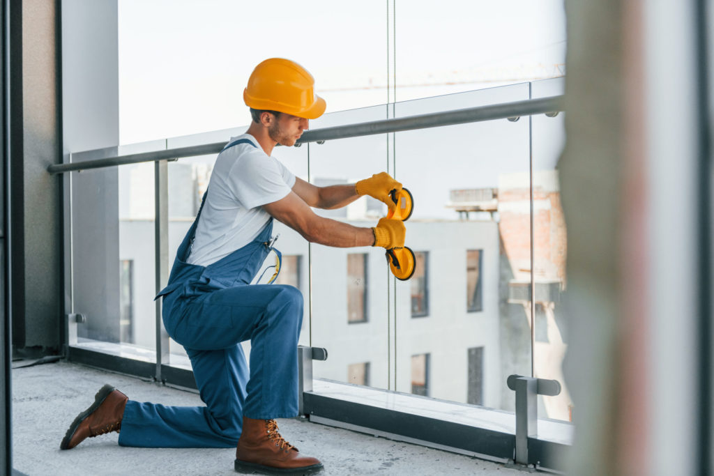 nstallation of windows. Young man working in uniform at construction at daytime.